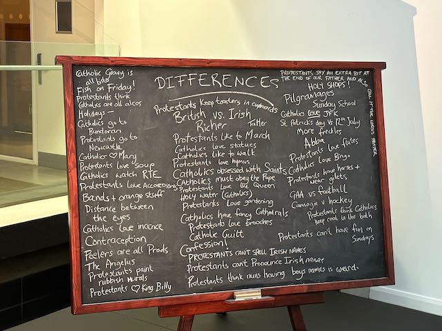 Black chalk board with writing showing the differences between Catholics and Protestants on.
