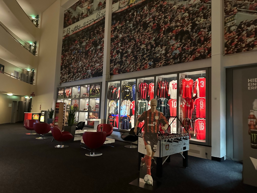 LOBBY OF THE BAYER LEVERKUSEN HOTEL RESTAURANT WITH LOTS OF SHIRTS AND A CUT OUT OF A FOOTBALL PLAYER